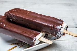 gros plan de barre de chocolat à la crème glacée fondante. crème glacée recouverte de chocolat sur fond de bois photo