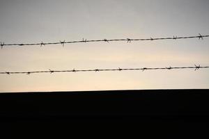 clôture en fil de fer barbelé avec ciel crépusculaire pour se sentir silencieux et solitaire et vouloir la liberté photo