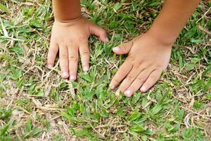 les mains des enfants et les mains de la mère touchent l'herbe et la terre. photo