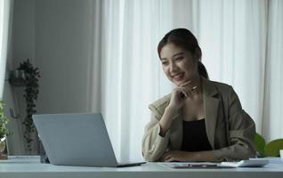 la jeune femme d'affaires asiatique est heureuse de travailler au bureau moderne à l'aide d'une tablette. photo