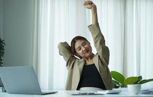 jeune femme d'affaires asiatique étirant les bras levés se relaxant au bureau. photo