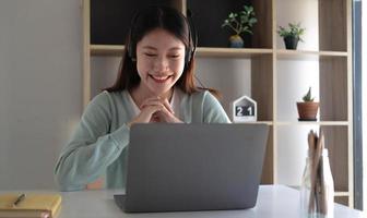 les étudiants asiatiques intelligents trouvent satisfaction en étudiant en ligne sur Internet et en rencontrant des amis pour rechercher des informations sur leurs ordinateurs portables à la maison. photo