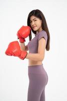 portrait d'une belle femme asiatique souriant debout portant les gants de boxe rouges, prise de vue en studio isolée sur fond blanc, concept de remise en forme, d'exercice et de santé photo