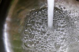 l'eau courante d'un robinet d'eau dans le drain d'un évier chromé. photo