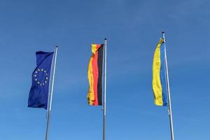 les drapeaux de l'ukraine, de l'allemagne et de l'union européenne volent côte à côte contre le ciel bleu. photo