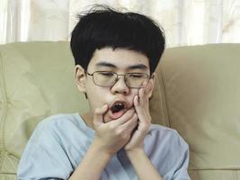 petit garçon asiatique souffre de maux de dents. il est triste avec des douleurs dentaires, une maladie dentaire, un enfant souffrant de problèmes dentaires. prévoyez de rendez-vous chez le dentiste. photo