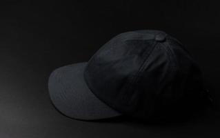chapeau de casquette en tissu noir sur fond noir foncé. photo