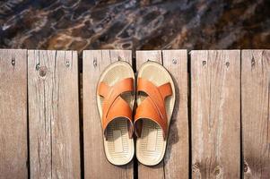 sandales en cuir sur un chemin en bois vers la mer photo