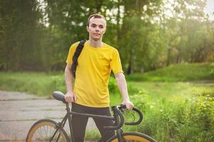 un jeune homme s'est arrêté pour se reposer avec son vélo dans un parc public. photo