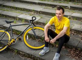 un jeune homme s'est arrêté pour se reposer avec son vélo dans un parc public. photo