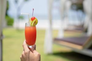 homme asiatique détendu sur la plage avec son cocktail de citron vert à la main lors de l'ouverture de la journée d'été photo