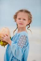 petite fille adorable buvant du lait de coco sur la plage photo