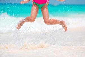 adorable petite fille s'éclaboussant dans l'eau tropicale peu profonde pendant les vacances d'été photo
