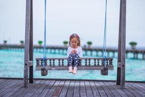 silhouette d'adorable petite fille sur balançoire au coucher du soleil photo