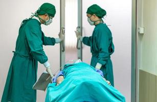 focus sélectif de l'équipe médicale déplaçant le patient en chirurgie dans la salle d'opération de l'hôpital photo