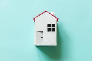concevez simplement avec une maison de jouet blanche miniature isolée sur un fond tendance coloré pastel bleu. concept de maison de rêve d'assurance de propriété hypothécaire. espace de copie plat vue de dessus. photo