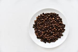 grains de café torréfiés sur une assiette blanche photo