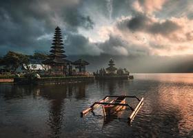 ancien temple de pura ulun danu bratan avec bateau traditionnel sur le lac bratan au lever du soleil à bali photo