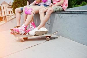 photo en gros plan des jambes masculines sur planche à roulettes et des jambes féminines en rollers et protection.