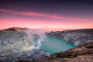 volcan de cratère actif avec de la fumée de soufre dans un lac turquoise avec un ciel coloré le matin