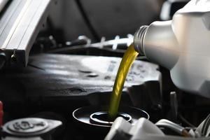 verser de l'huile moteur dans le moteur de la voiture. huile fraîche versée lors d'un changement d'huile dans une voiture. photo