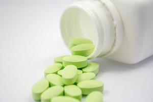pilules vertes et bouteille de pilules sur fond blanc photo