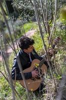 garçon joue de la guitare entouré par la nature photo