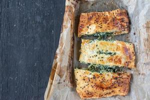 pâte feuilletée aux épinards tranchés et au fromage avec graines de sésame noir photo