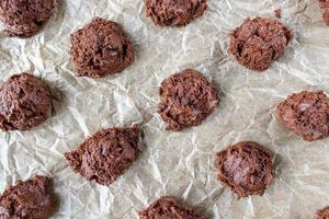 Évider la pâte à biscuits aux pépites de chocolat sur une plaque à biscuits en papier ciré mise à plat photo