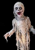 portrait tourné en studio d'un jeune garçon en costume habillé en halloween, cosplay de momie effrayante pose sur fond noir isolé photo