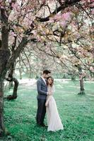 belle mariée et le marié heureux étant douchés de confettis de fleurs de cerisier photo