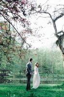 belle mariée et le marié heureux étant douchés de confettis de fleurs de cerisier photo