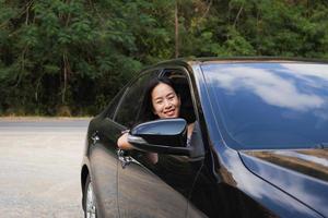 femme joyeuse regardant par la fenêtre de la voiture sourit à la caméra. photo