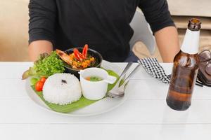 homme mangeant du plat thaïlandais célèbre pad kra pao stream riz aux crevettes royales en vacances. photo