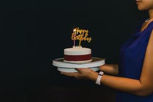 femme tenant un gâteau d'anniversaire avec une bougie et une assiette d'anniversaire. photo