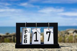 17 février texte de la date du calendrier sur cadre en bois avec arrière-plan flou de l'océan photo
