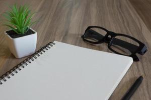 bloc-notes avec lunettes, stylo et plante en pot sur un bureau en bois photo