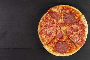 pizza au four avec saucisse sur la table en bois noir photo