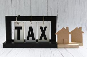 texte d'impôt sur support papier cadre noir avec modèle de maison sur fond de bois blanc photo