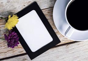 cadre de tableau avec des fleurs de dahlia et une tasse de café blanche sur un bureau en bois. photo