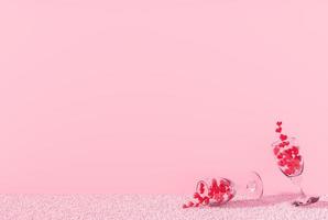 De nombreux coeurs rouges dans un verre de vin sur un tapis rose dans la salle des murs roses
