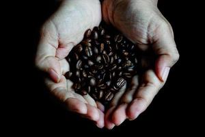 grains de café dans les mains de forme de coeur sur table en bois style sombre photo