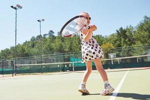 heureuse petite fille jouant au tennis photo