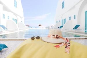 chapeau d'été et lunettes de soleil sur sac de haricots jaunes avec fond de piscine photo