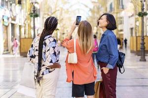 dames multiraciales prenant un autoportrait sur un téléphone portable dans la rue