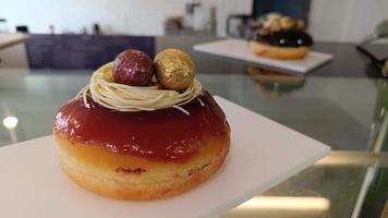 beignet glacé aux fraises et décoré d'oeufs de pâques rouges et or sur une plaque blanche photo