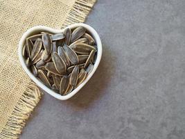 graines de tournesol dans une tasse blanche en forme de coeur sur fond de ciment. concept d'aliments sains. photo