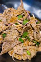 La salade de foie de porc épicée thaïlandaise est un aliment célèbre du nord-est de la Thaïlande. le foie de porc bouilli est mélangé avec du riz rôti moulu, des échalotes aux herbes thaïlandaises, de la ciboule, du culantro et des ingrédients d'assaisonnement. photo
