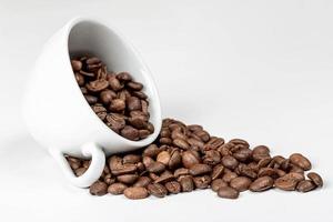 grains de café dans une tasse de café sur blanc photo