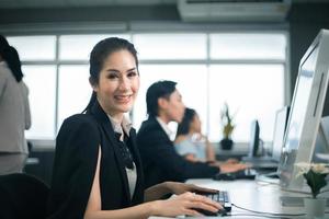 les femmes d'affaires décontractées souriantes utilisent un ordinateur portable au bureau